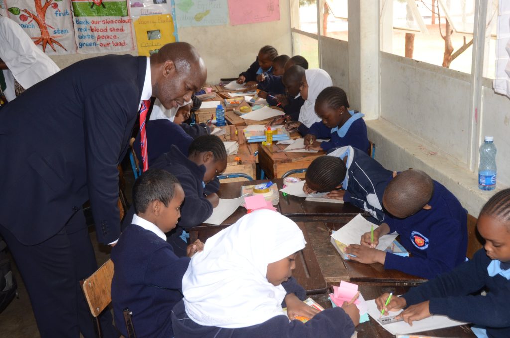 The Director General, Department of Basic Education in the Republic of South Africa Hubert Mweli follow a lesson in grade three class room at the Visa Oshwal Primary School. SA Government wants Kenya to help it to introduce Kiswahili in her schools. Photo/ Courtesy
