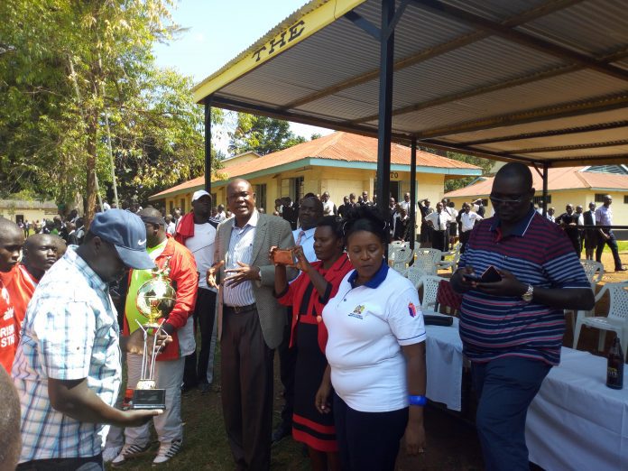 Nyanza Region's Sports Chair, Mr. Moses Adala in checked coat, addressing Regional Championship participants at a past event. With him is the Regional Secretary, Mr. Tom Thomas Odhiambo; holding a trophy. Nyanza Region's Sports Chair, Mr. Moses Adala in checked coat, addressing Regional Championship participants at a past event. With him is the Regional Secretary, Mr. Tom Thomas Odhiambo; holding a trophy.