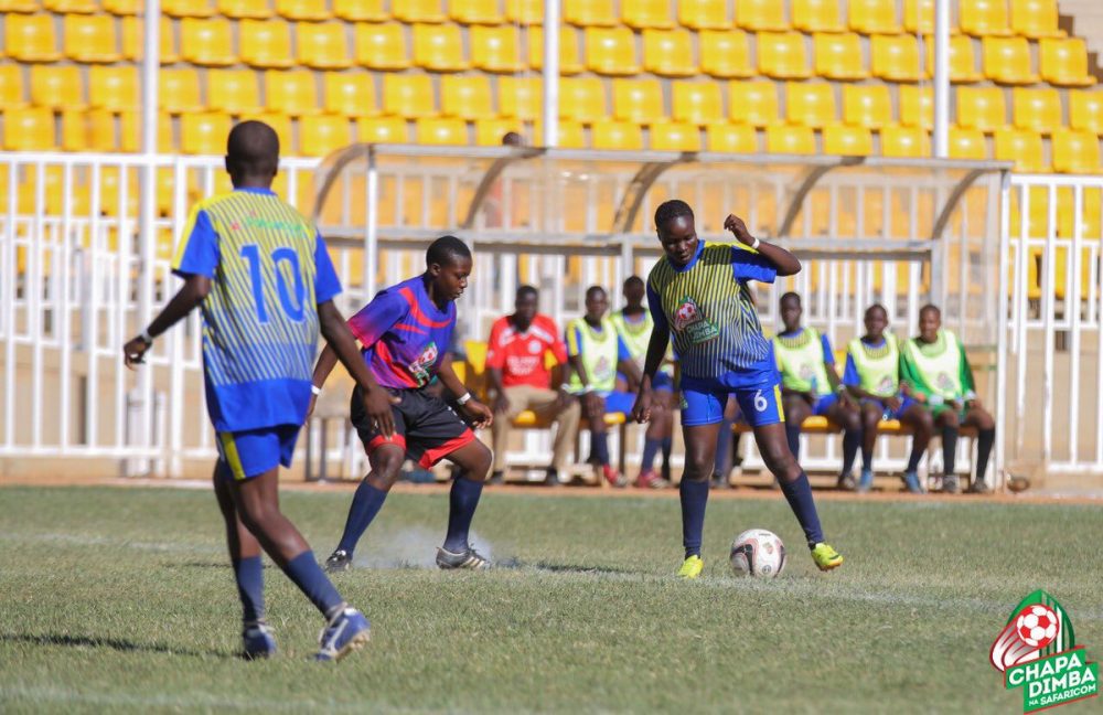An Arch Bishop Njenga's player, in blue red stripped top, is sandwitched between two Ibinzo players in a during a pulsating girlrs' final in the Western Region 2019 Chapa Dimba na Safaricom. Arch Bishop Njenga won 2-0