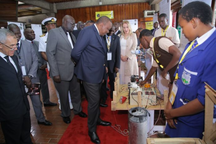IMG_20190806_060524 Photo- H.E President Uhuru Kenyatta (Left) looks at an innovation project by students when he opened the second Young Scientists Kenya National Science and Technology Exhibition at KICC, Nairobi, on Saturday August 3, 2019. The President encouraged the key stake holders to help commercialize these great innovations .